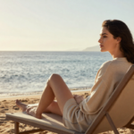 Sommer, Sonne, Stress? Warum die Urlaubszeit trotz Erholung überfordern kann Nachdenkliche Frau sitzt auf einem Liegestuhl am Strand und blickt aufs Meer. Symbolbild für Sommerstress, innere Unruhe und Achtsamkeit im Urlaub.