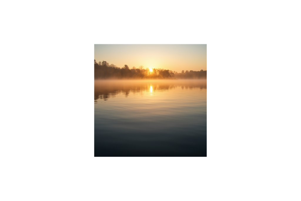 Ruhiger See bei Sonnenaufgang mit Spiegelung im Wasser und sanftem Nebel
