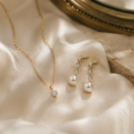 Perlenohrringe mit Diamanten und feine Goldkette auf elfenbeinfarbenem Seidenstoff