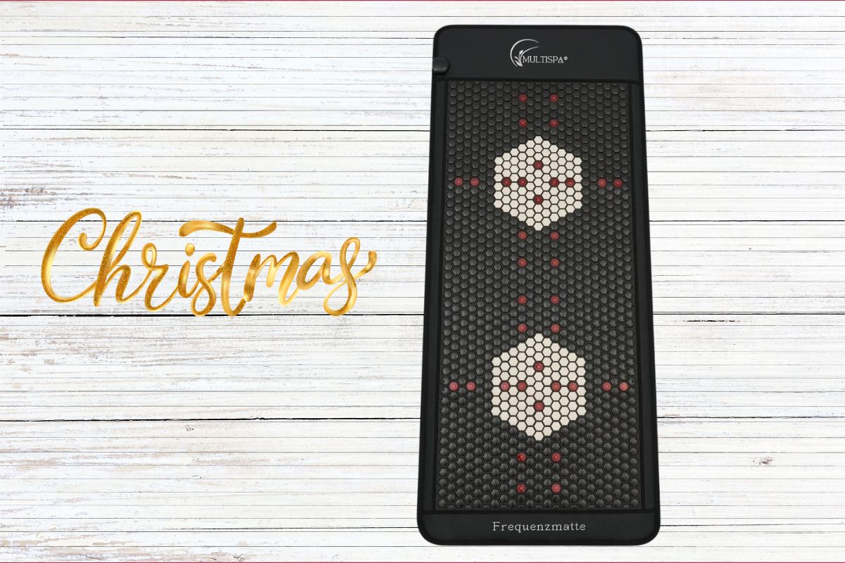 MultiSpa Frequenzmatte auf hellem Holzuntergrund neben dem goldenen Schriftzug „Christmas“.